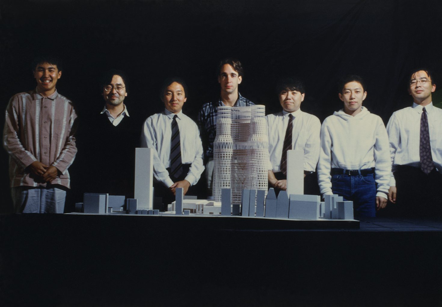 A group of people standing behind an architectural model